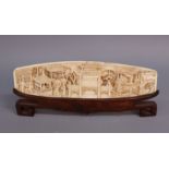 A Chinese carved ivory panel depicting figures in a village, 8 3/4" x 2 1/2" high, on carved