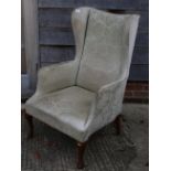 A high wing backed fireside chair, on cabriole supports
