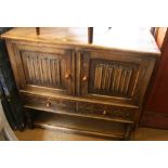 An oak side cabinet, fitted cupboard enclosed two linen-fold panel doors over two shallow drawers,