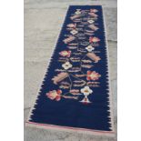 A kelim runner with floral design on a blue ground, 122" x 35" approx