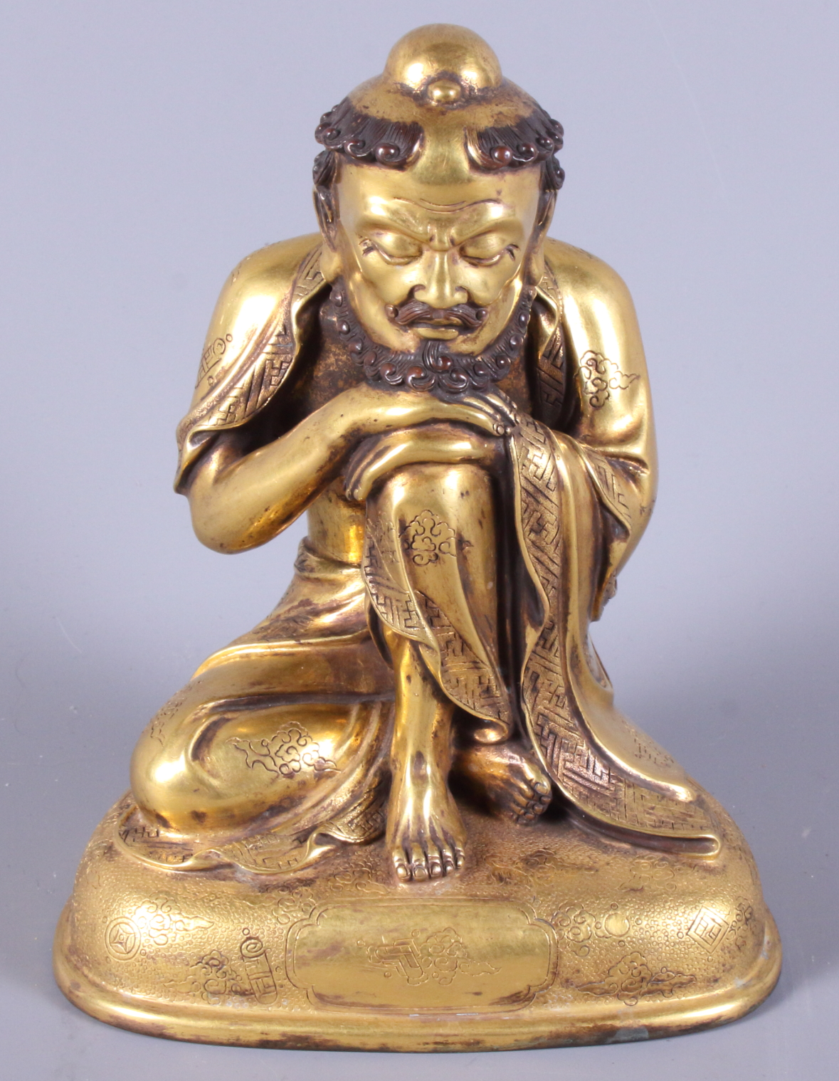 A late 19th century Chinese gilded figure of a crouching bearded man, engraved various Buddhist