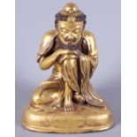 A late 19th century Chinese gilded figure of a crouching bearded man, engraved various Buddhist