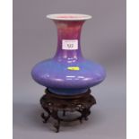 A Chinese purple flambe glazed pottery squat globular shaped vase, on hardwood stand with four