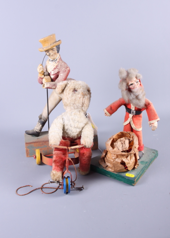 A pull-along teddy on a tricycle, a figure of Santa Claus and a figure of Johnny Walker (some