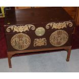 An Oriental brown lacquered blanket box with front decorated gilt roundel and bat motif, on stand