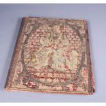 An antique needlework and silver thread folio cover depicting a seated saint on a velvet ground (