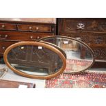 An Edwardian oval bevelled wall mirror, in line inlaid mahogany frame, and another oval mirror, in