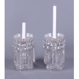 A pair of Edwardian clear glass table candlestick lustres with hanging prism drops, on shaped