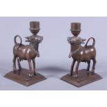 A pair of 20th century Indian cast brass candlesticks, in the form of oxen, each on rectangular