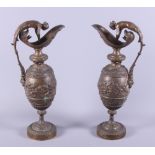 A pair of late 19th Century bronze ewers, cast with cherubs, the scroll handle in the form of a nude