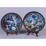 A matched pair of early 20th century Japanese cloisonne chargers, decorated with cranes flying