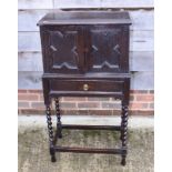 An oak side cabinet, the upper section enclosed two fielded panel doors over one drawer, on barley