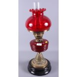 A late Victorian/early 20th century brass and ruby glass oil lamp, 23" high, together with two