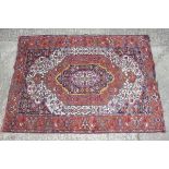 A Herati rug with all-over floral design and central medallion in shades of white, blue, rust,
