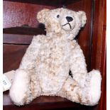 An early 20th century beige mohair seated teddy bear with black glass eyes and articulated limbs, 13