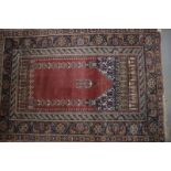 A Persian prayer rug with mihrab and central pendant on a rust ground and numerous border stripes,