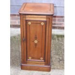 An Aesthetic movement walnut bedside cupboard with ebonised and decorated panel door, on block base,