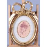 A pair of oval colour prints, portrait sketches, in carved giltwood frame with ribbon surmount,