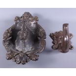 A late 19th century cast iron boot scraper, moulded with shaped rim and masks of Bacchus's head, and