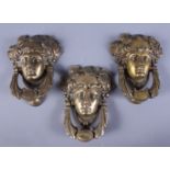 A group of three brass door knockers, in the form of a Roman soldier's head, the knocker cast in the