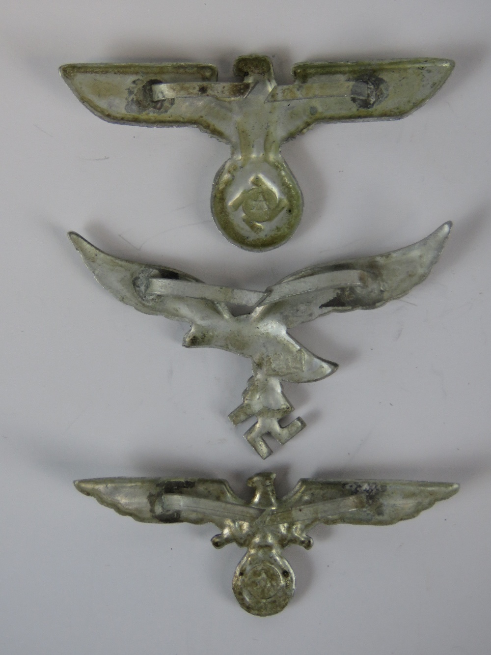 Three WW2 Nazi German white metal cap badges; with two stamped "A" verso. - Image 2 of 2