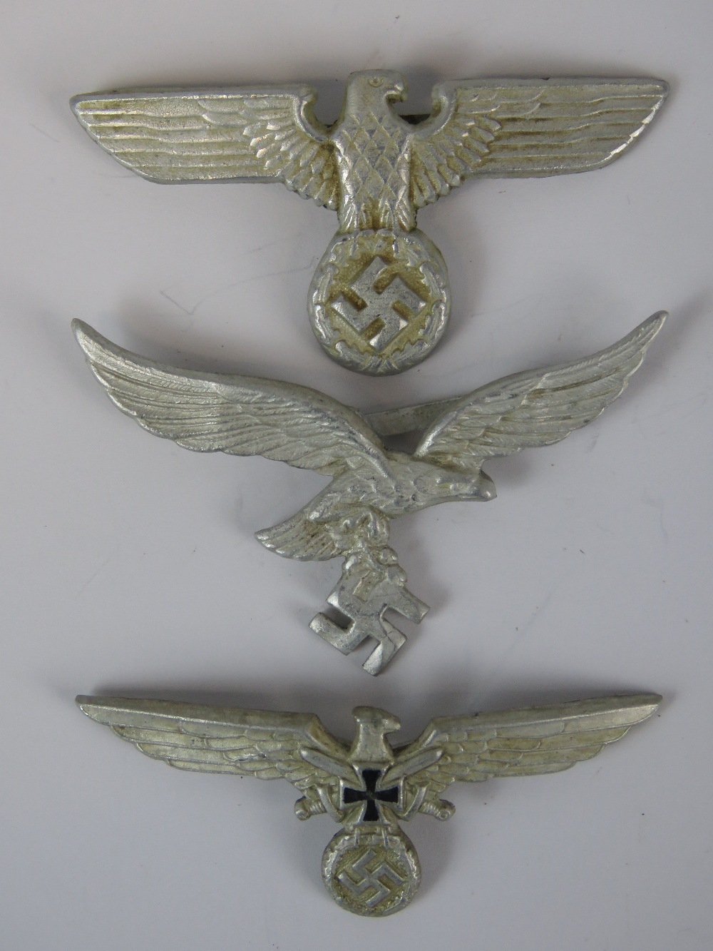 Three WW2 Nazi German white metal cap badges; with two stamped "A" verso.