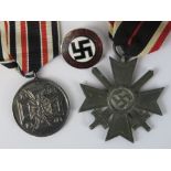 An enamel Nazi Party badge (with RZM M 1/128 verso) together with two reproduction Nazi German