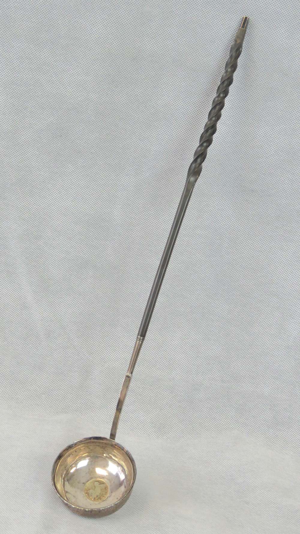 A white metal toddy ladle with twist pattern handle.