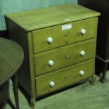 A Victorian stripped pine chest of three drawers having matching cream ceramic handles. 77cm wide.