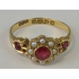 An 18ct gold ruby and seed pearl ring, central round cut ruby surrounded by seed pearls,
