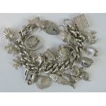 A heavy HM silver curb link charm bracelet with HM silver heart padlock clasp and twenty-one charms