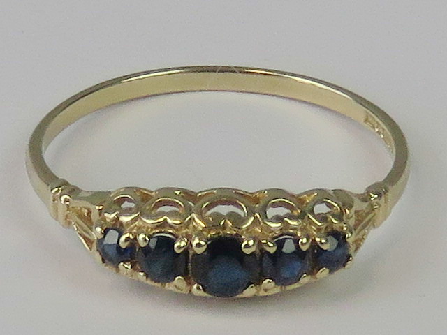 A 9ct gold five stone sapphire ring, graduated round sapphires claw set in pierced yellow metal,