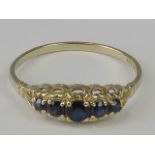 A 9ct gold five stone sapphire ring, graduated round sapphires claw set in pierced yellow metal,