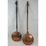 Two 19thC copper warning pans each having a long, turned fruitwood handle.