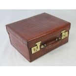 A vintage brown leather crocodile skin travelling case having single handle and brass fittings.