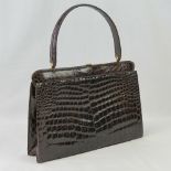 A vintage brown leather crocodile skin handbag having single loop handle and brass fittings.