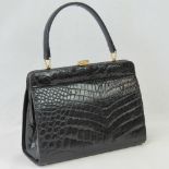 A vintage black leather crocodile skin handbag having single loop handle and brass fittings.