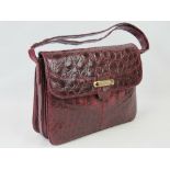 A vintage burgundy leather crocodile skin handbag having single loop handle and brass fittings.