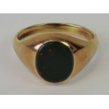 A 9ct gold signet ring with uncarved bloodstone oval plaque, hallmarked 375, size S,