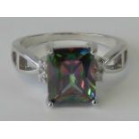 A silver and mystic topaz ring, large emerald cut topaz flanked by two pairs of small white stones,