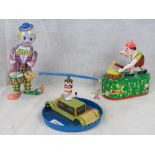 Three Chinese made contemporary tin plate toys; clown, woodchopper, and centrifugal toy.