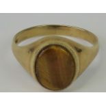 A 9ct gold signet ring with uncarved tigers eye oval plaque, hallmarked 375, size T-U, 3.