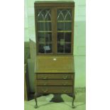 A c1930's bureau bookcase having twin glazed doors over fall-front base,