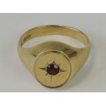 A 9ct gold signet ring with central garnet in star setting, hallmarked 375, size W, 7.2g.