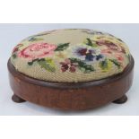 An early 20th century upholstered foot stool embroidered with roses, with a mahogany base.