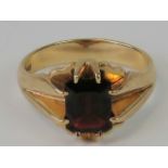 A 9ct gold and garnet ring, emerald cut garnet claw set in yellow metal hallmarked 375, size S, 5.