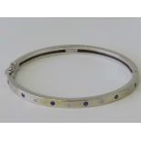 A 9ct white gold diamond and sapphire hinged bangle,