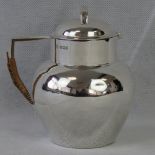 A HM silver Arts and Crafts hot water jug with wicker covered handle,