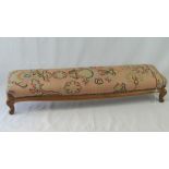 A fine quality long and sloped footstool having needlepoint upholstery and raised over squat