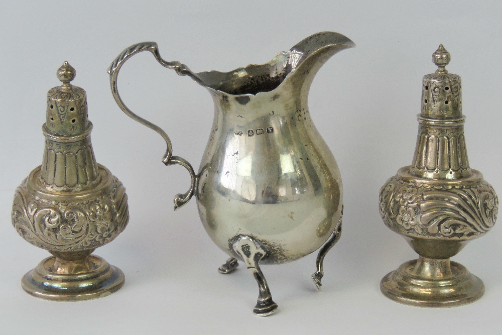 A HM silver cream jug, Birmingham 1920, and a pair of HM silver pepperettes, Birmingham 1911.